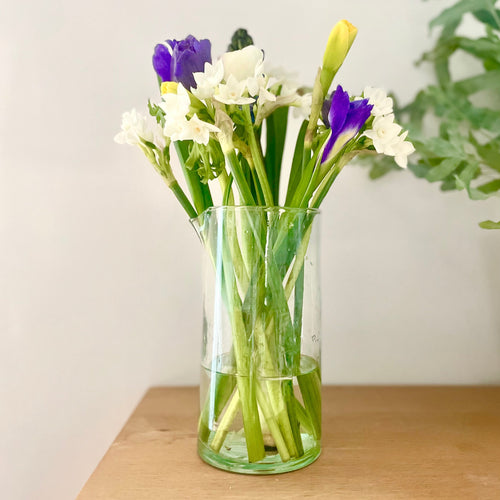 Clear glass vase with flowers on a wooden surface