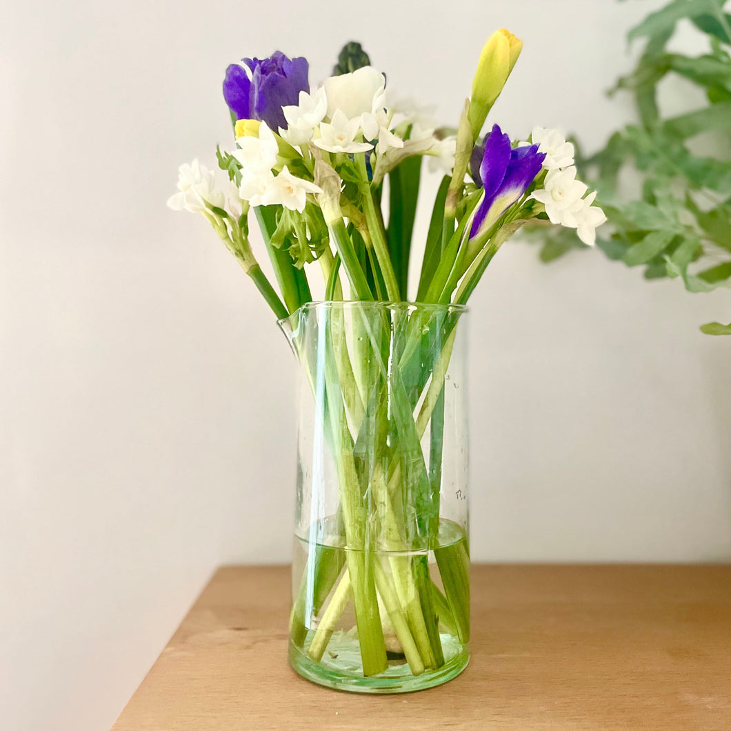 Clear glass vase with flowers on a wooden surface